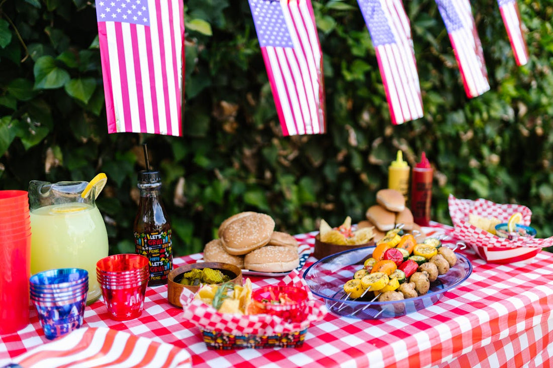 Spread of grilled food, summer sides, and red-white-and-blue table decor for a Fourth of July celebration, illustrating a Space Coast holiday catering menu.