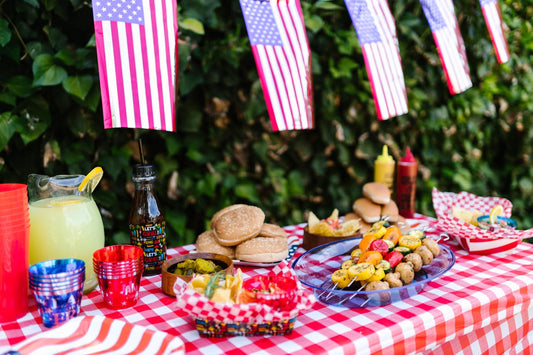 Spread of grilled food, summer sides, and red-white-and-blue table decor for a Fourth of July celebration, illustrating a Space Coast holiday catering menu.
