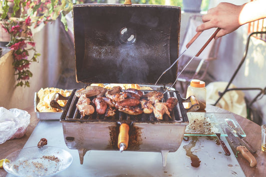 Assorted meats and vegetables grilling at an outdoor summer cookout