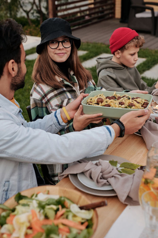 Family gathered around an outdoor table sharing a meal in a backyard
