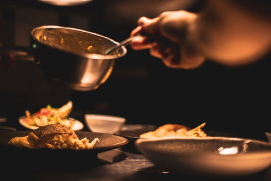 Chef carefully plating a gourmet course by hand in a warmly lit kitchen