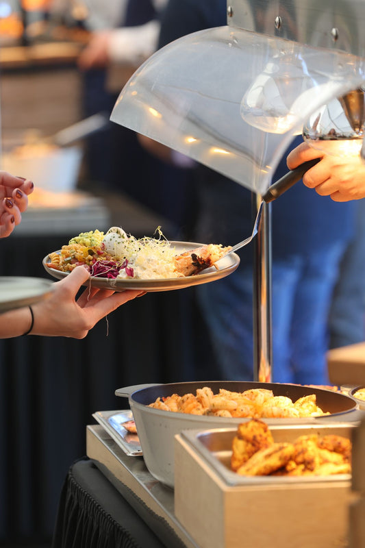 Guests serving themselves from a catered buffet line of assorted dishes under warm lighting