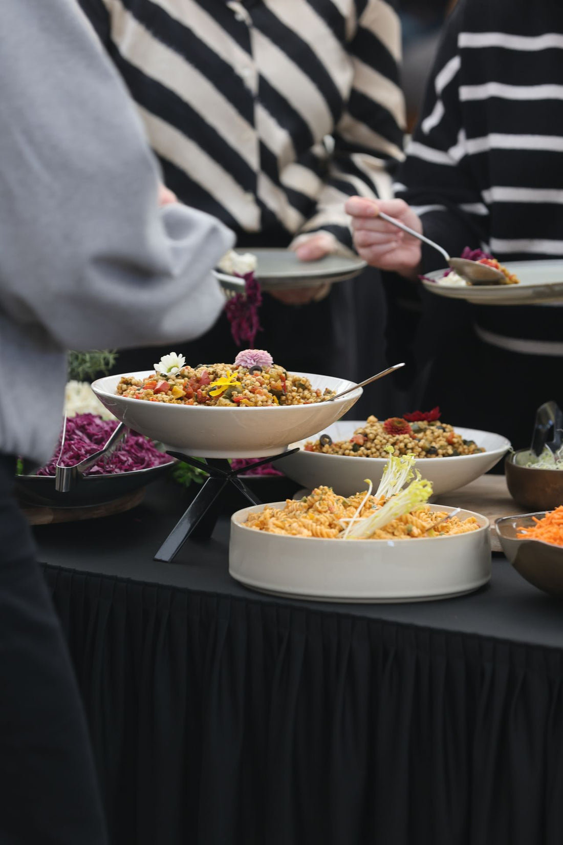 Guests serving assorted dishes onto plates from a warmly lit catering buffet line