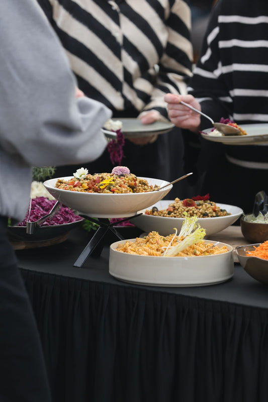 Guests serving assorted dishes onto plates from a warmly lit catering buffet line