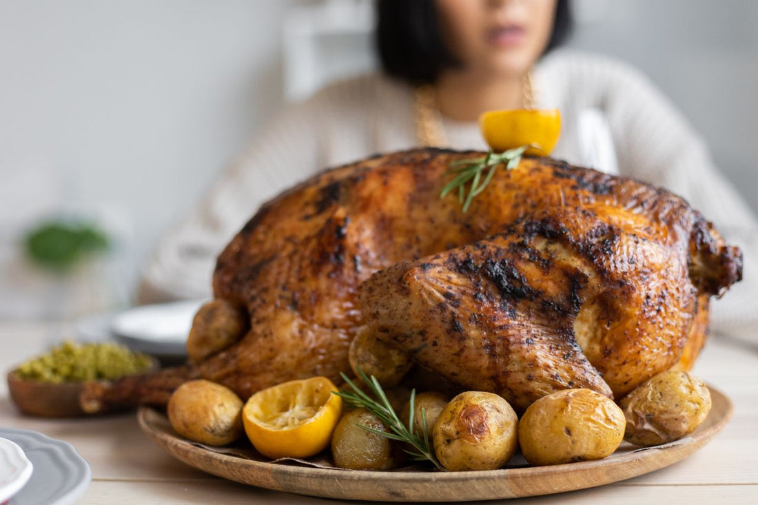 Roasted turkey with potatoes and lemon on a round wooden tray set on a table
