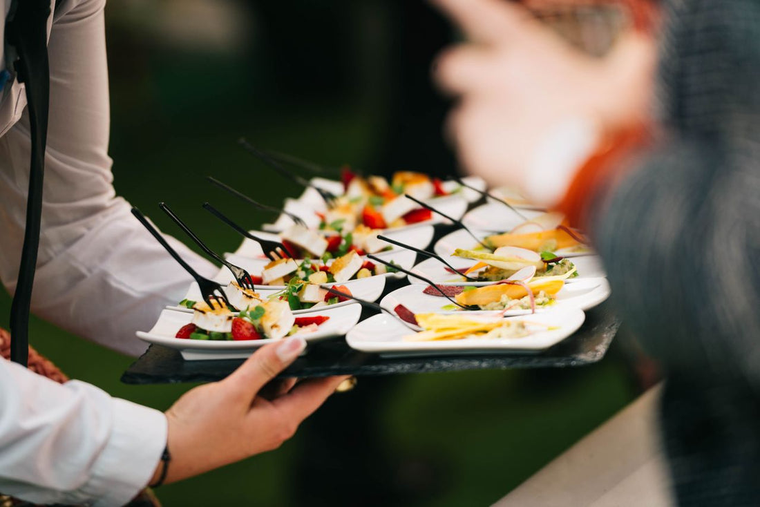 An elegant holiday-themed catering spread with appetizer stations set up for a corporate office party